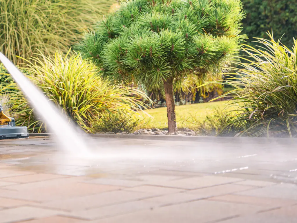 High-pressure water spray cleaning a concrete driveway in Williamstown, NJ — blasting away algae, tire marks, oil stains, and years of embedded grime from residential concrete.