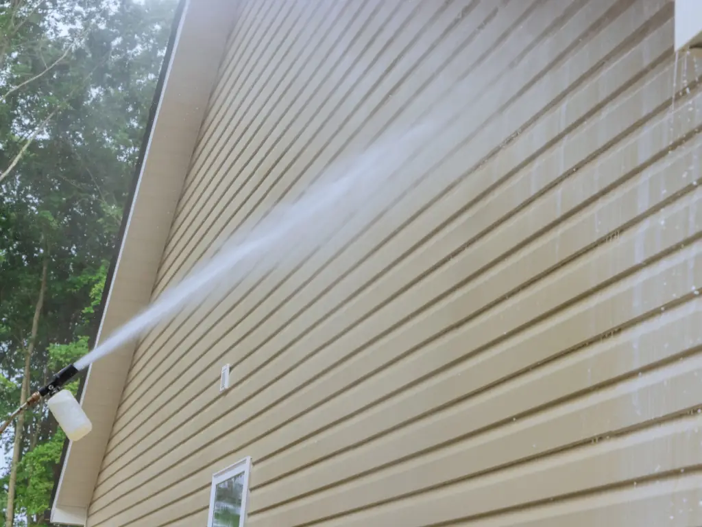 Professional exterior wall and siding pressure washing on a shore home — removing salt deposits, oxidation, and algae from coastal property exteriors.