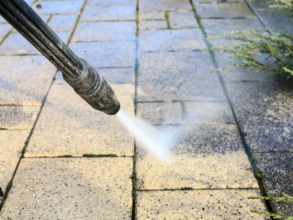 Pressure washing a stone paver patio walkway reveals a clean surface during an exterior property cleaning service.