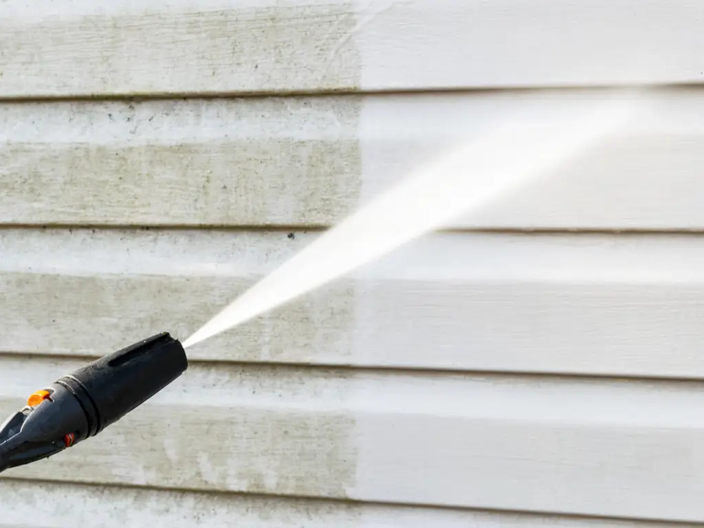 Pressure washing white vinyl siding on a house in Cherry Hill, NJ — removing green algae, dirt, and grime for a clean, like-new exterior finish.