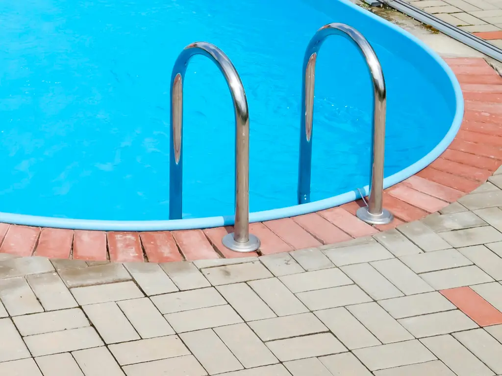 Pressure washing inground pool handrail and steps on a Stone Harbor, NJ property — cleaning salt buildup, algae, and mineral deposits from pool surrounds and entry points.