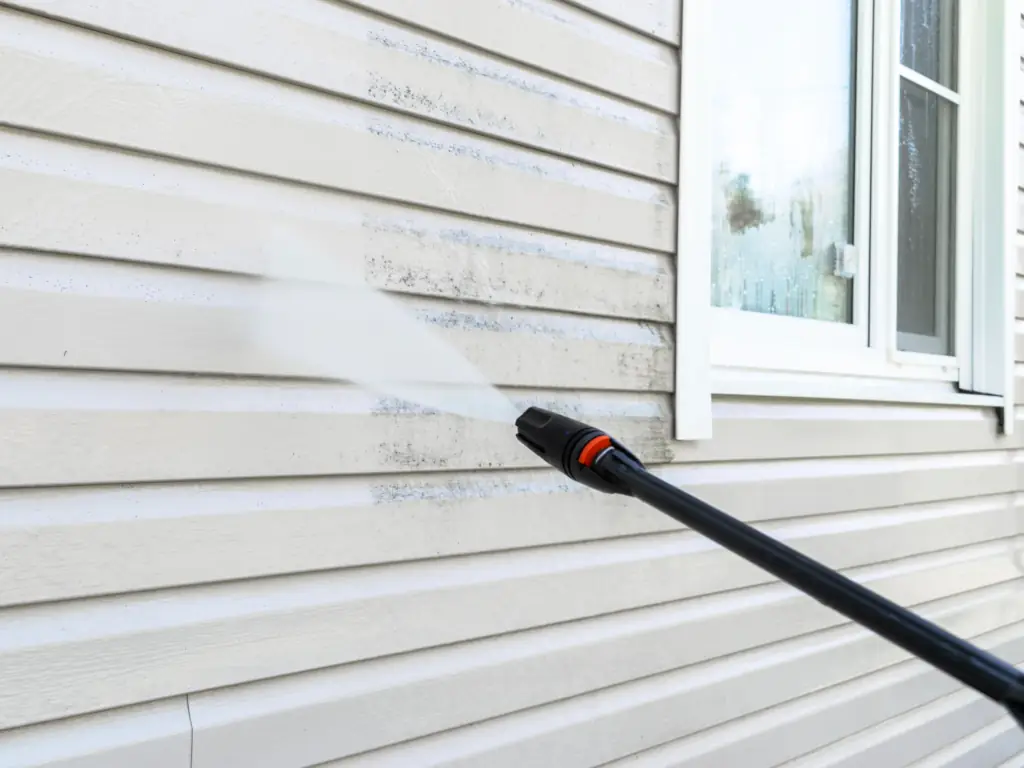 Power washing mold and algae from vinyl siding on a Stone Harbor, NJ shore house — removing dark biological staining from coastal exterior siding panels.