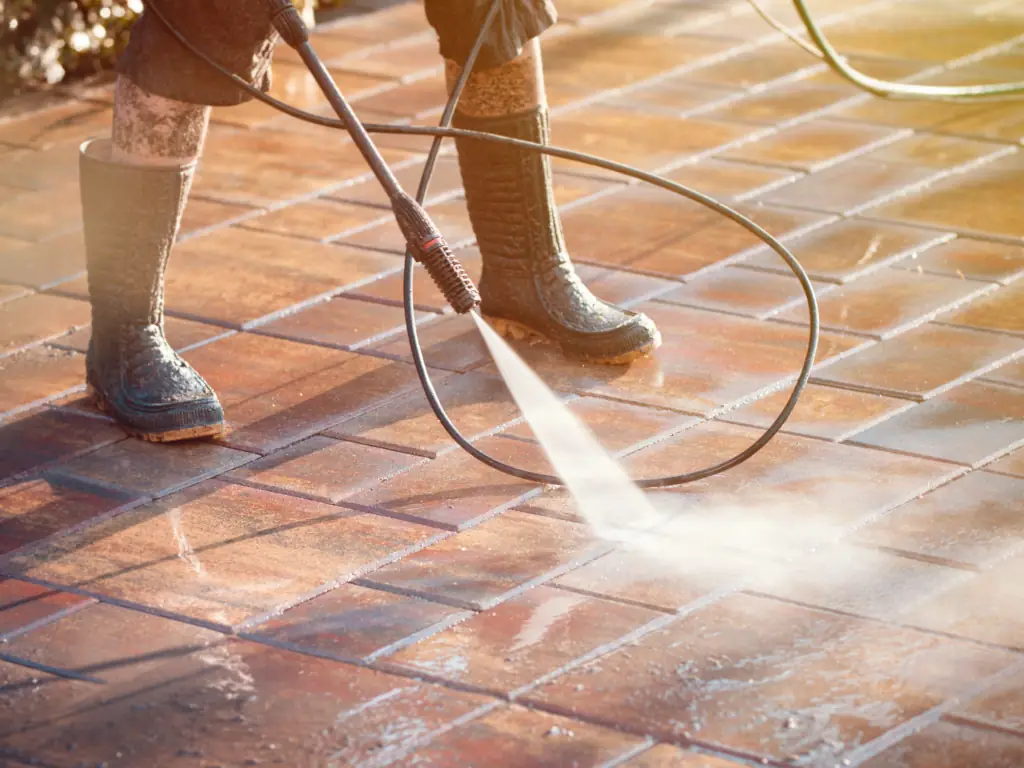 Pressure washing outdoor concrete patio tiles on a Mount Laurel, NJ property — removing algae, staining, and embedded grime from outdoor living area surfaces.