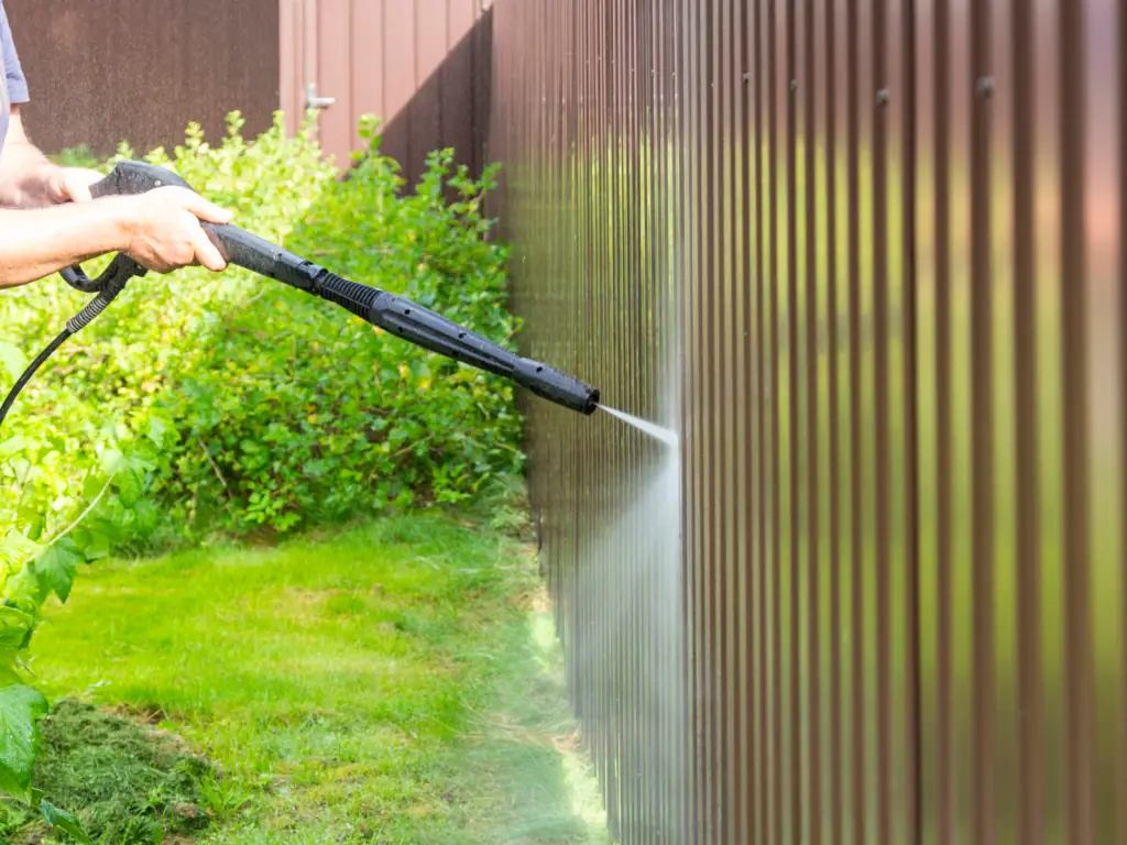 Pressure washing a residential garden fence in Collingswood, NJ — removing algae, mildew, and grime from wood and metal fence panels in shaded yards.