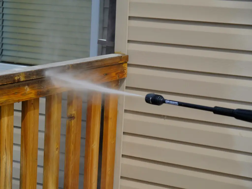Pressure washing a wood deck banister and railing on a Sea Isle City, NJ shore house — removing salt residue, algae, and weathered grime from barrier island deck structures.