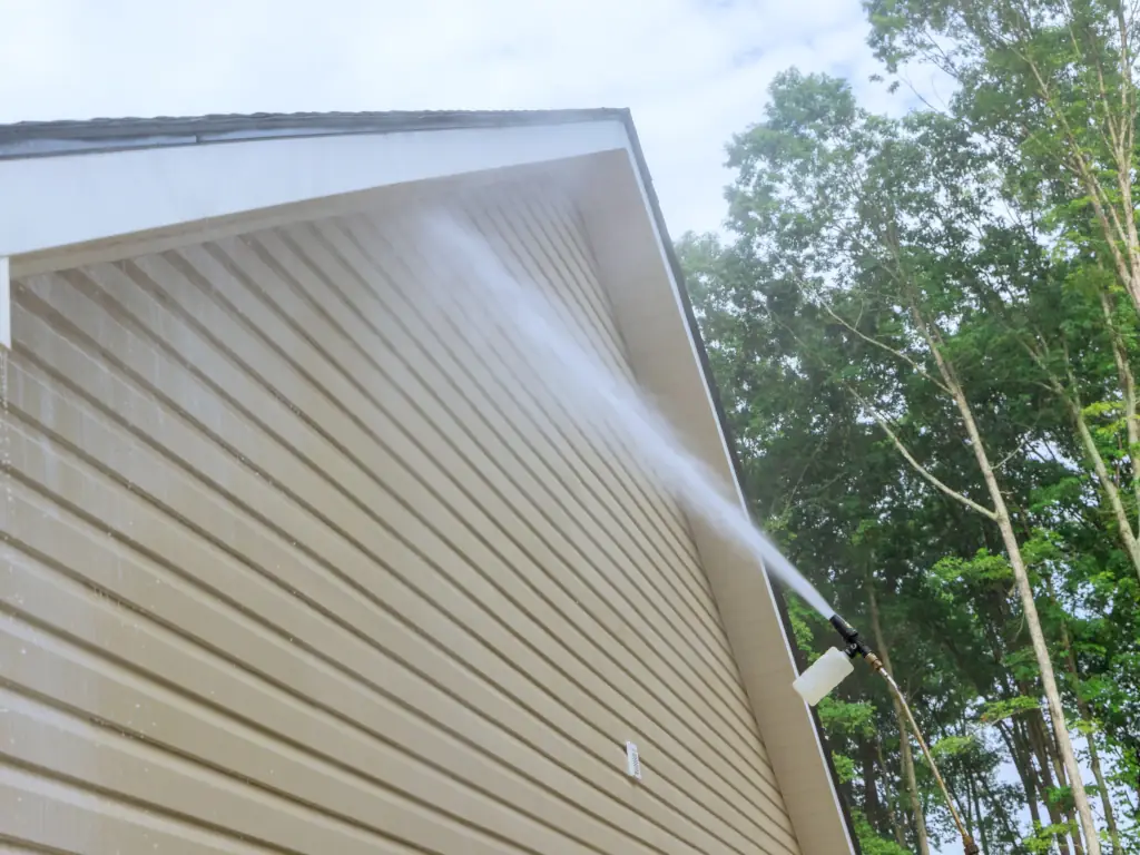 High-reach pressure washer soft washing vinyl siding on a Williamstown, NJ home — removing algae streaks, mold, and built-up grime from exterior siding and soffit areas.